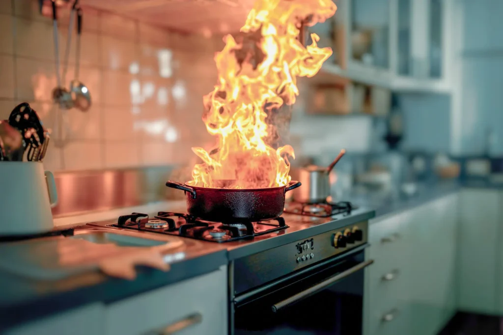 Flammen schlagen aus einem Topf auf einem Herd in der Küche.